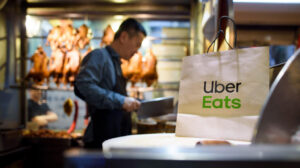 Medium shot of a paper food bag on a table while a chef cutting meat with a cleaver in background